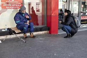 Homeless Prints: Belgrade, Serbia, Jan 1, 2021: A homeless man and female photographer having conversation at Glavna Street in Zemun