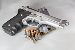 Beretta 92FS or M9 hand gun and pack of bullets 9mm parabellum isolated on reflection surface