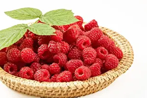 Berries of ripe raspberries in a wicker basket on a white background