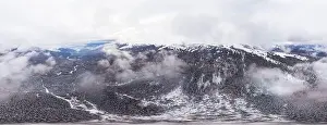 Hill Glacier Prints: Bewitching beautiful panorama of mountains and hills covered with fir trees on a winter cloudy day