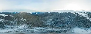 Hill Glacier Prints: Bewitching beautiful panorama of mountains and hills covered with fir trees on a winter cloudy day