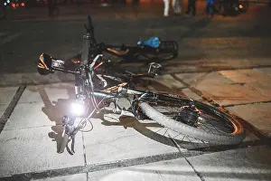 Black City Prints: A bicycle parked at night on a city street with a light lamp on