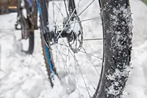 Offroad Prints: A bicycle wheel with winter spikes in the snow on a winter road