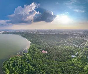 Summer Green Prints: Big lake with green shores in bright sun light and city on horizon
