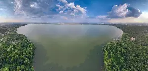 Summer Green Prints: Big lake with green shores in bright sun light and city on horizon