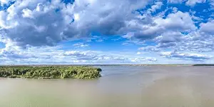 Summer Green Prints: Big lake with green shores in bright sun light and city on horizon