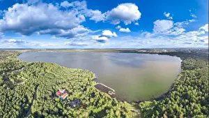 Summer Green Prints: Big lake with green shores in bright sun light and city on horizon