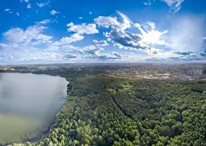 Summer Green Prints: Big lake with green shores in bright sun light and city on horizon