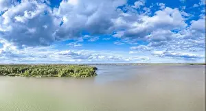 Summer Green Prints: Big lake with green shores in bright sun light and city on horizon