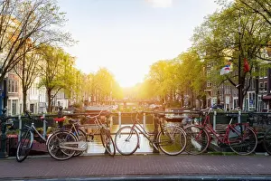 Bike over canal Amsterdam city in Netherlands with view on river Amstel during sunset