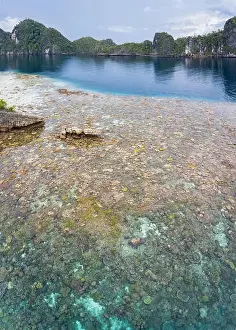 A bird's eye view shows healthy reefs surrounding remote limestone islands in Raja Ampat. This area is known for its incredible marine biodiversity