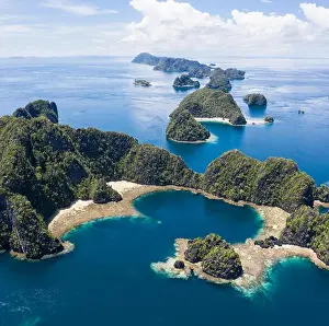 A bird's eye view shows healthy reefs surrounding remote limestone islands in Raja Ampat. This area is known for its incredible marine biodiversity