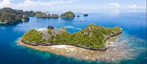 A bird's eye view shows healthy reefs surrounding remote limestone islands in Raja Ampat. This area is known for its incredible marine biodiversity