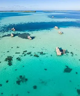 A bird's eye view shows a rustic Indonesian fishing village constructed on a coral reef near remote, tropical islands in the Halmahera Sea