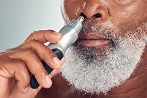 Black Man Prints: Black man, grooming and nose hair removal with an electric trimmer for shave