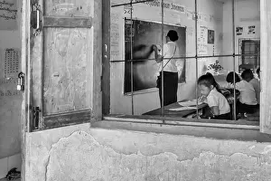 Laos Prints: Black and white view from the window of a teacher writing on the blackboard in a school in Vang Vieng
