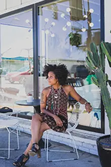 Afro Prints: Black woman sitting at a table outside a cafe
