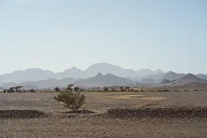 Saudi Arabia Prints: bleak desert landscape of reddish sands with mountain and rock formations in northern Saudi Arabia