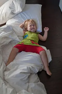 Cushion Prints: blonde caucasian baby two years old green dress red shorts lying on bed white clothes