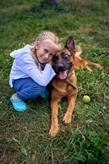 German Shepherd Prints: blonde girl of 8 years old hugs a German shepherd dog