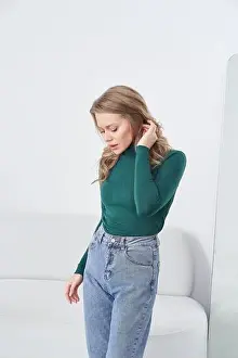 Airy Prints: Blonde woman in green long-sleeve top and blue jeans stands indoors with head slightly tilted