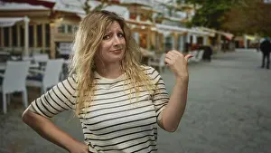 Boulevard Prints: Blonde woman points thumb to street near outdoor restaurant terrace