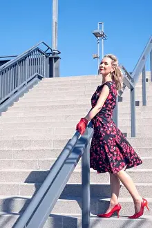 Fifties Prints: blonde woman in a red dress standing on stair steps and enjoying the sun