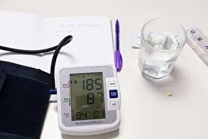 Medical Care Prints: Blood pressure device notebook and pills on a white table