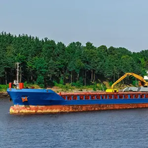 Underway Prints: Blue cargo ship with long reach excavator moving to the port