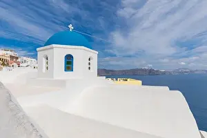 Blue dome in Santorini, Fira. Summer vacation landscape, peaceful sea view and volcanic cliff. Caldera view, cloudy sky
