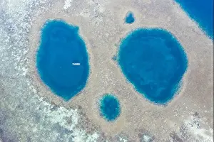 Blue holes are found amid a shallow reef flat on the island of Sebayor in Komodo National Park, Indonesia. These blue holes formed as sink holes
