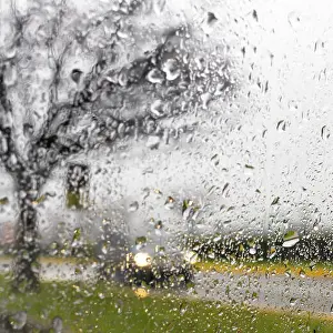 Street Light Prints: Blurry car silhouette seen through water drops on the car windshield