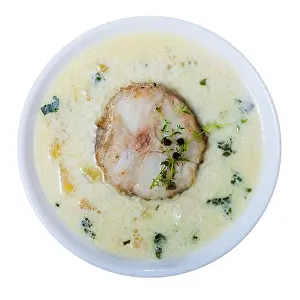 Over White Prints: Boiled creamy soup with white fish pollock and greens at plate