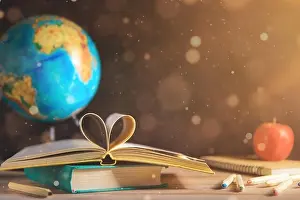 Books, globe, apple and stationery lie on the table against the chalkboardof a black blackboard. Education, September 1, new academic year with copy s