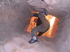 Desperation Prints: Boy climbing up a vertical tunnel in the underground city in Maz köy Cappadocia central Anatolia Turkey