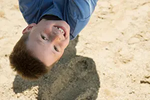 Weekend Activities Prints: Boy hanging upside down from rope in playground, Munich, Bavaria, Germany