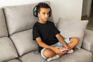 Concentrated Prints: Boy in headphones playing video game on couch