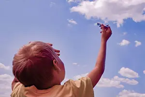 Throw Prints: the boy looks at the airplane in his hands against the blue sky