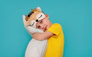 Pajama Prints: a boy in pajamas hugging a pillow. Banner with blue background and copy pasta