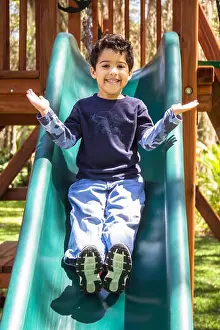 Primary Age Child Prints: Boy in playground sliding down a slide