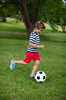 Real Life Prints: Boy playing football in park on sunny a day
