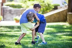 Rival Prints: Two boys fighting outdoors. Siblings or friends wrestling on grass in summer park