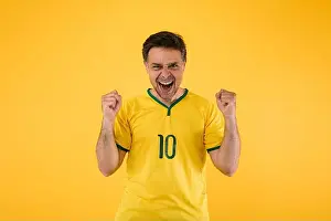 Soccer Ball Prints: Brazilian soccer fan in a yellow jersey clenches his fists and yells cheering for his team