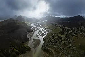 Breathtaking drone view of river estuary in sunlit valley amidst mountains in cloudy morning in Iceland