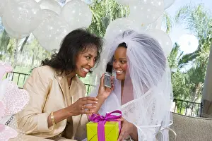 Veil Prints: Bride using mobile phone with mother at bridal shower