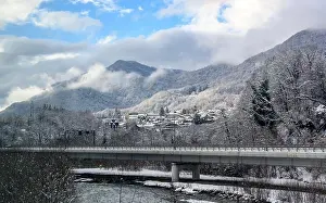 Village Mountain Prints: A bridge over a mountain river and a village covered with snow on the background of mountains in fog