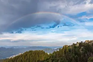Bright multicolored natural rainbow with different colors on a light daytime cloudy sky