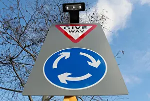british road sign indicating a roundabout ahead and instructing road users to give way on reaching it