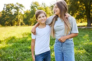 Siblings Prints: Brother and sister hugging happily in green park on summer vacation