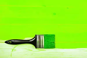 Repairing Prints: Brush with black handle on ufo green half painted wooden board. Renovation concept
